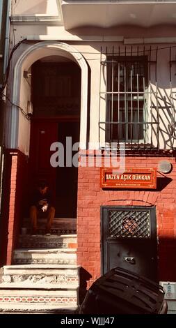 Vertical shot of a person sitting on the stairs in front of the entrance of a house Stock Photo