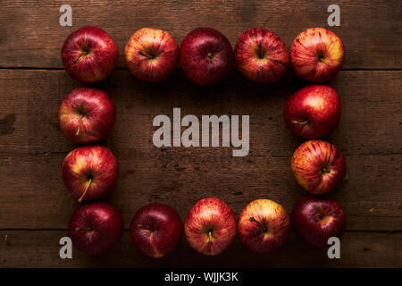 Deep red Royal Gala apples on a rustic wooden table with soft lighting Stock Photo