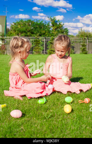 Adorable little girls having fun with Easter Eggs on green grass Stock Photo