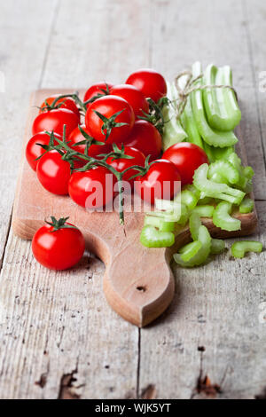 fresh organic celery and tomatoes on wooden board Stock Photo