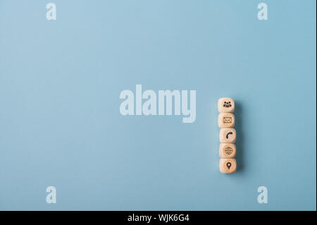 Five wooden dices with global contact and communication symbols on them stacked over blue background. With copy space. Stock Photo