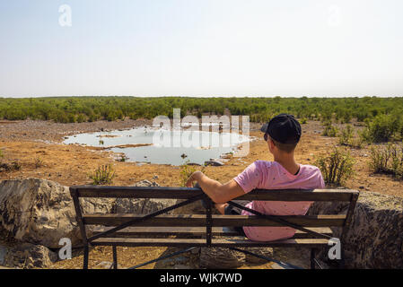 Tourist waits for wildlife at the Moringa waterhole near Halali, Etosha, Namibia Stock Photo