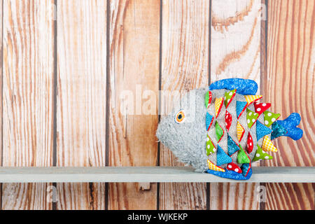 Stuffed colorful funny fantasy fish at home on wooden background Stock Photo