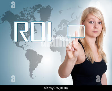Young woman press digital Return on investment button on interface in front of her Stock Photo
