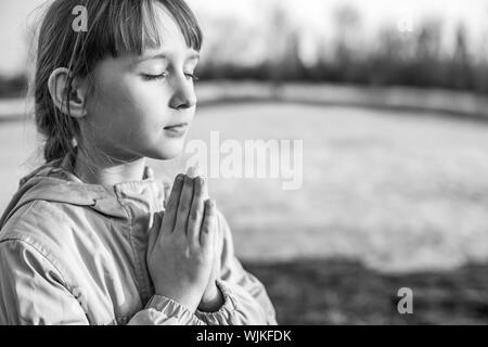 Young girl praying on the background of nature Stock Photo