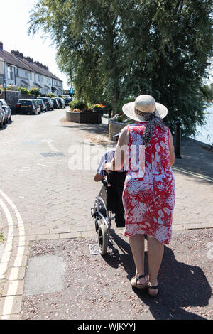 A middle aged woman pushing an elderly man in a wheelchair Stock Photo