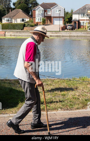 An elderly man taking a walk using a cane or walking stick Stock Photo