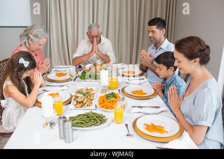 Family of six saying grace before meal at dining table in the house Stock Photo