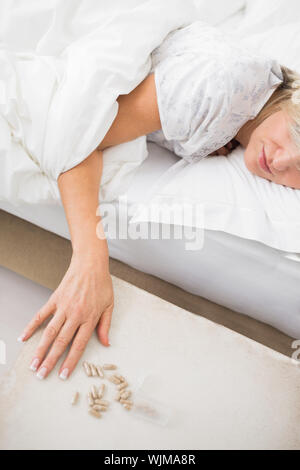 Closeup of a mature woman sleeping in bed with pills in foreground at home Stock Photo