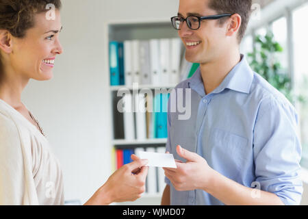 Smiling young business people exchanging visiting card in office Stock Photo