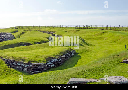 Broch of Gurness flanked by earth banks reinforced by stone. The broch village ruins surround it. Stock Photo