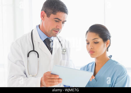 Concentrated doctor and nurse discussing over digital tablet in hospital Stock Photo