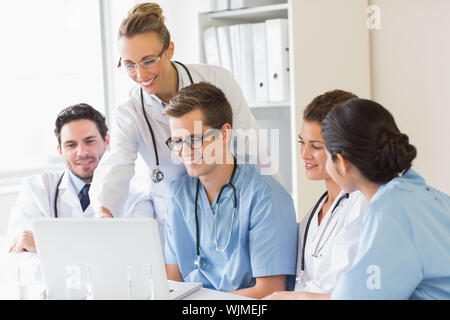 Smiling doctors and nurses discussing over laptop in hospital Stock Photo