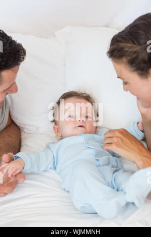 Caring parents playing with baby boy in bed Stock Photo