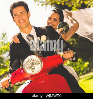 Portrait of a newlywed couple enjoying scooter ride Stock Photo