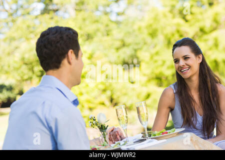 Smiling young couple with champagne flutes sitting at an outdoor caf&#xc3;&#xa9; Stock Photo