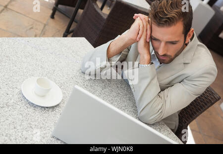 Businessman looking at his laptop at table having coffee in patio of restaurant Stock Photo
