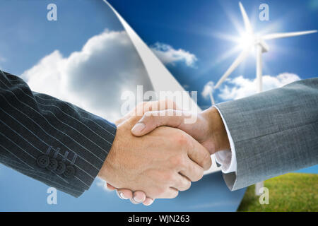 Composite image of business handshake against sky background over turbine background Stock Photo