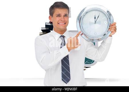 Anxious businessman holding and showing a clock against steps made out of books with open door Stock Photo