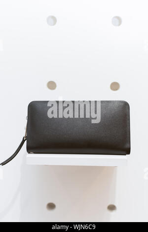 Black classic wallet on a shelf in a store. Long purse on a white background. Stock Photo