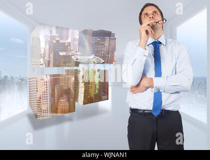 Thinking businessman biting glasses against bright white hall with windows Stock Photo