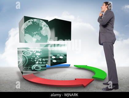 Thinking businessman with hand on chin against blue red and green arrows in desert landscape Stock Photo