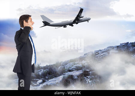 Thinking businessman scratching head against misty landscape Stock Photo
