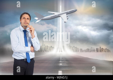 Thinking businessman biting glasses against open road Stock Photo