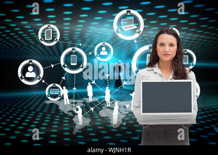 Brunette woman standing while showing a laptop screen against keyhole on technological glowing background Stock Photo