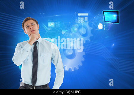 Thoughtful businessman with hand on chin against shiny cogs on blue background Stock Photo