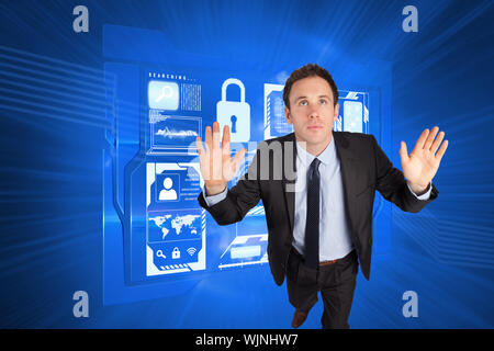 Businessman posing with arms raised against shiny cogs on blue background Stock Photo