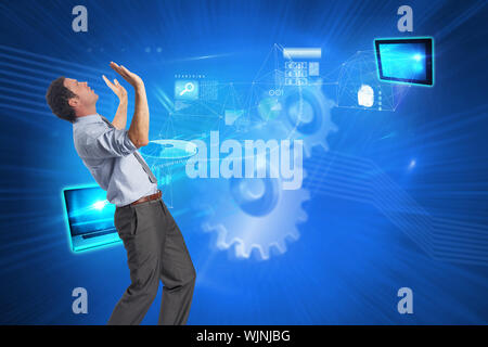 Businessman posing with arms raised against shiny cogs on blue background Stock Photo