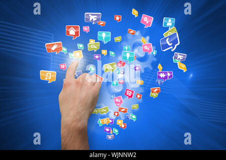 Hand pointing against shiny cogs on blue background Stock Photo