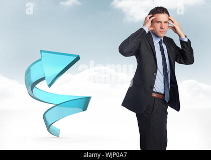 Stressed businessman with hands on head against blue spiral arrow in the sky Stock Photo