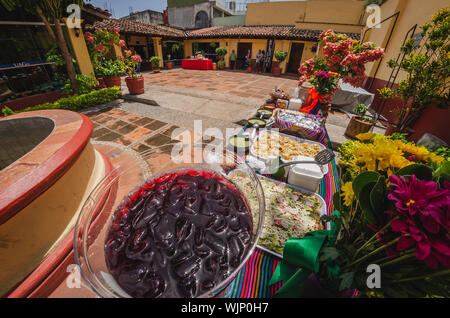 Big jar of cool jamaica water to refresh the customers on a mexican buffet party and a variety of mexican food served on trays Stock Photo