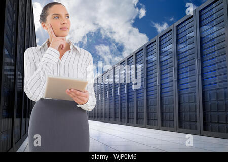 Confused businesswoman using a tablet pc against server hallway in the sky Stock Photo