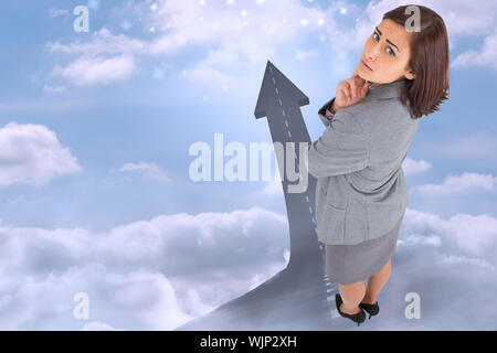 Worried businesswoman against road turning into arrow Stock Photo