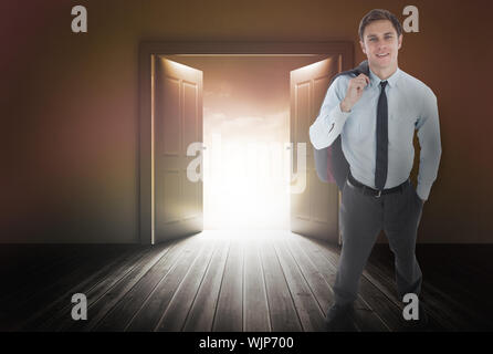 Smiling businessman holding his jacket against door revealing bright light Stock Photo