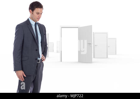 Serious businessman with hand on hip against door opening revealing bright light Stock Photo