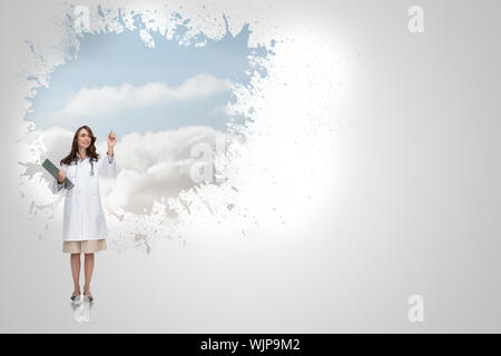 Smiling doctor pointing against splash on wall revealing clouds Stock Photo