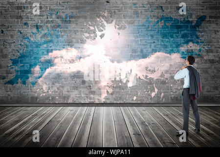 Businessman holding his jacket against splash on wall revealing clouds Stock Photo