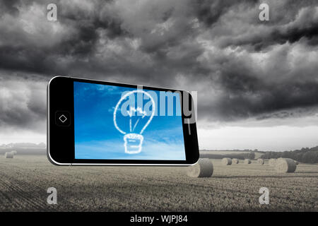 Cloud light bulb on smartphone screen against misty landscape with bales of straw Stock Photo