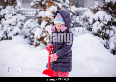 Little girl play with snow shoveling on a winter day Stock Photo