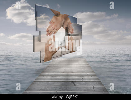 Hands making a house on abstract screen against bridge in ocean under cloudy sky Stock Photo