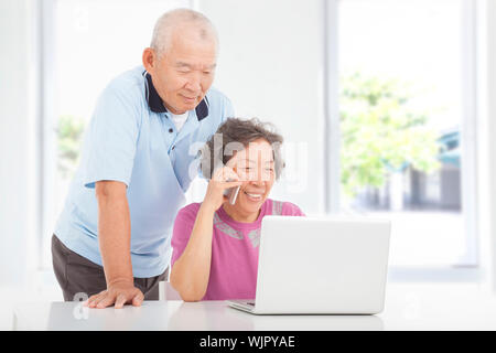Senior couple using a laptop and a cell phone  at home Stock Photo
