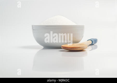 Bowl filled with sugar in white reflective surface Stock Photo
