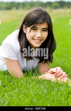 Beautiful biracial teen girl relaxing on lush green grass Stock Photo