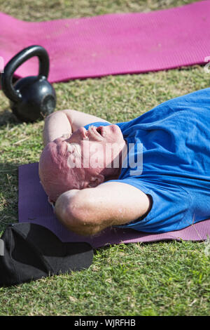Exhausted man laying on mat after working out Stock Photo