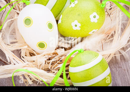Collection of four hand decorated colourful green Easter eggs with different patterns displayed in straw, close up view Stock Photo