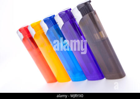Row of vividly coloured plastic disposable lighters for smokers in red, yellow, two shades of blue and black isolated on a white background Stock Photo